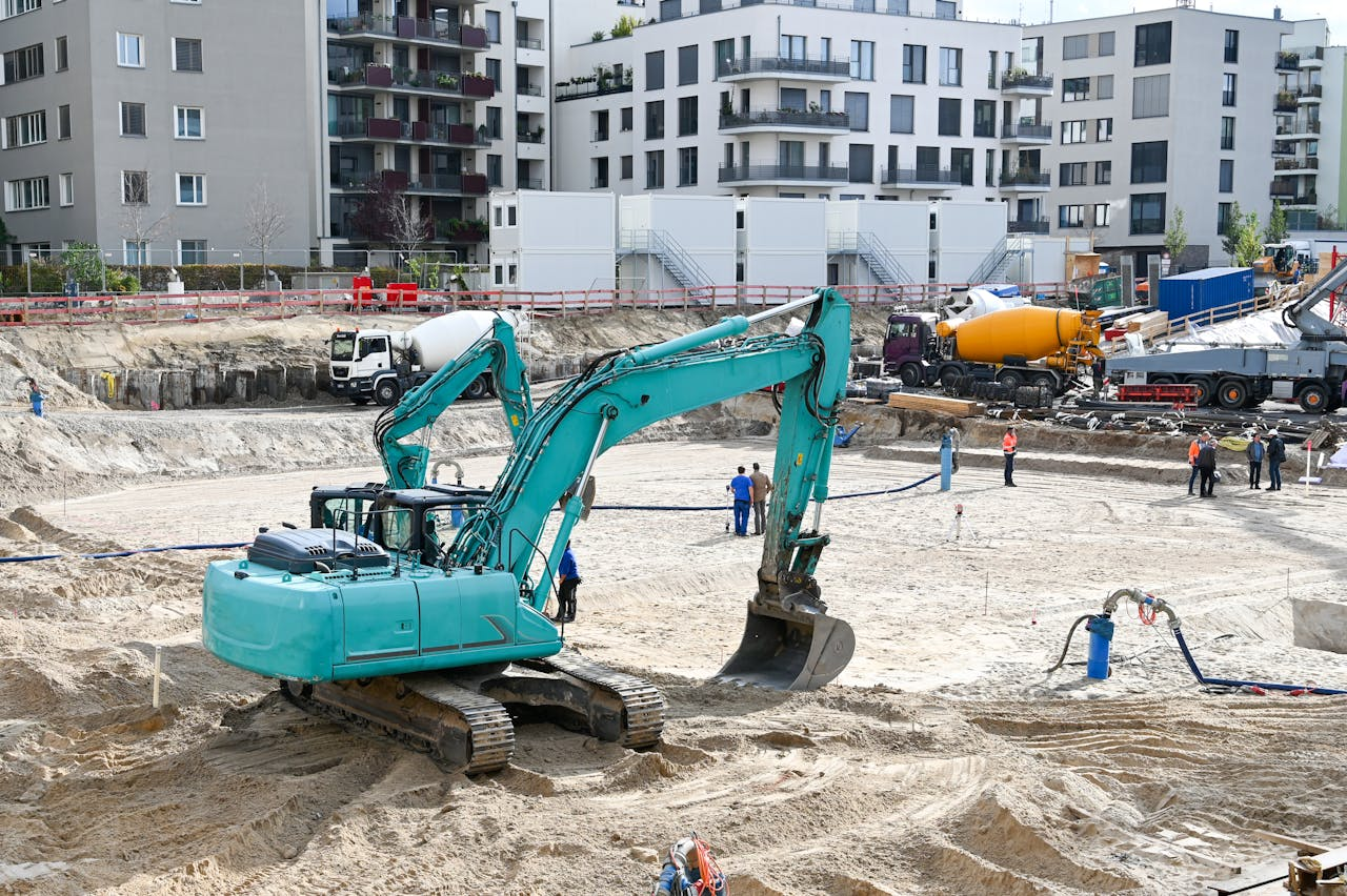 our-journey-01 A busy construction site with machinery, workers, and residential buildings in the background.