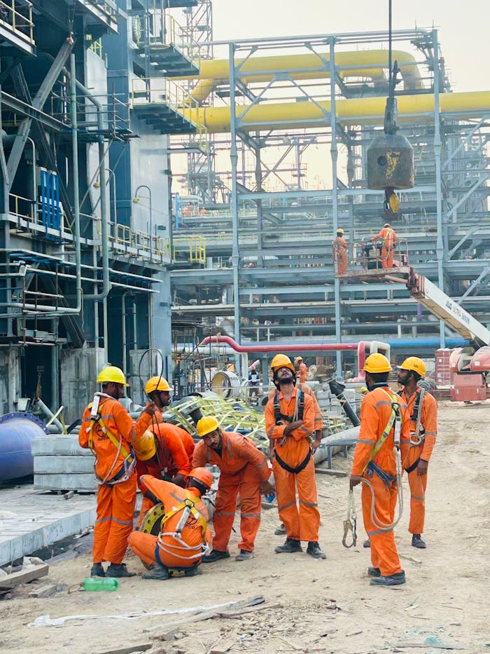 our-journey-03 Group of construction workers in orange uniforms operating at an industrial site.