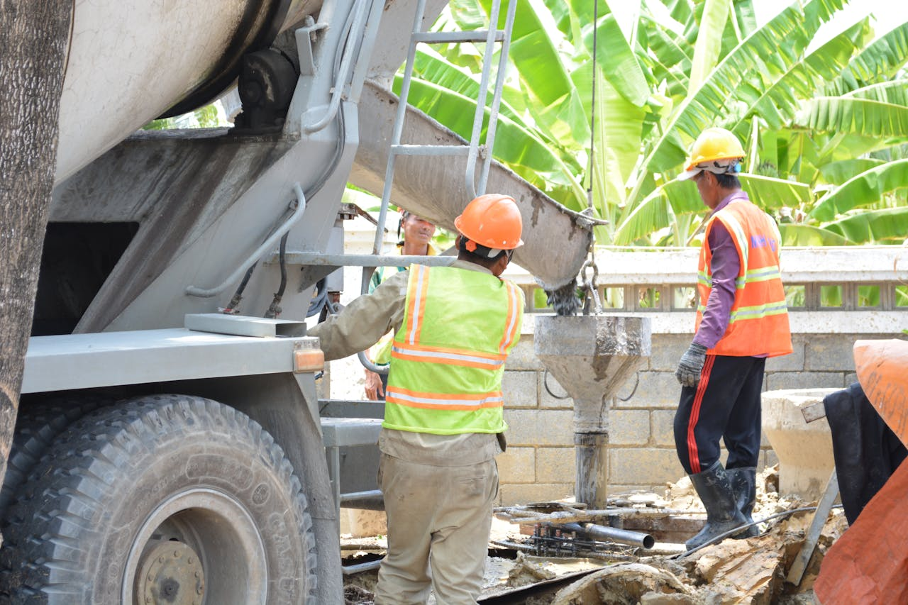 Construction site with workers pouring concrete from a truck chute outdoors.